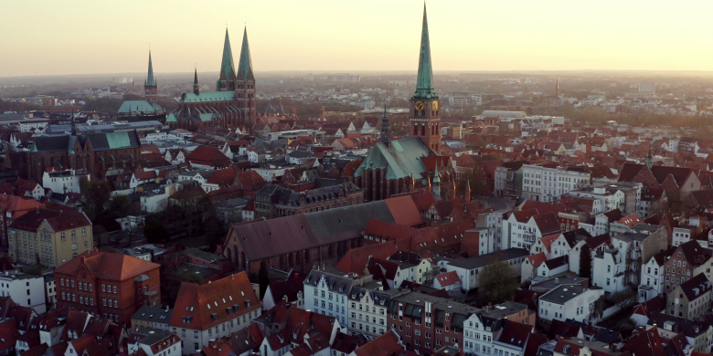 Eine Drohnenaufnahme, die die Altstadt von Lübeck, Travemünde mit dem Skandinavienkai und Umgebung aus der Luft zeigt